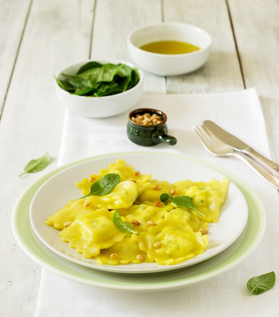 Ravioli with ricotta and spinach, served with olive oil and pine nuts