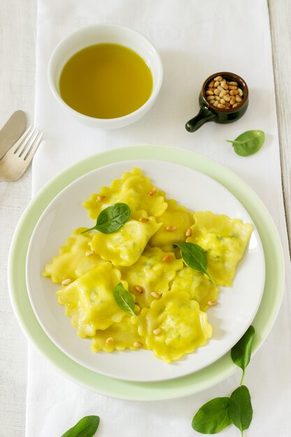 Ravioli with ricotta and spinach, served with olive oil and pine nuts