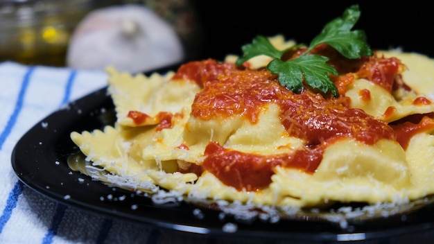 黒い皿にトマト、チーズ、パセリをのせたラビオリ