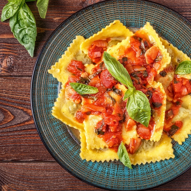 Ravioli con salsa di pomodoro e basilico su fondo scuro