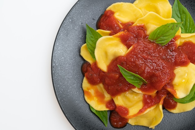 Ravioli with tomato sauce and basil isolated on white table