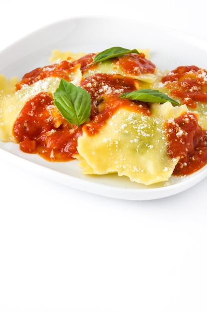 Ravioli with tomato sauce and basil on white wall