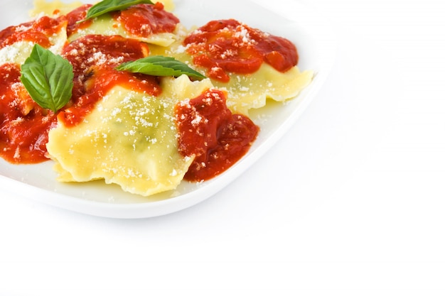 Ravioli with tomato sauce and basil on white wall