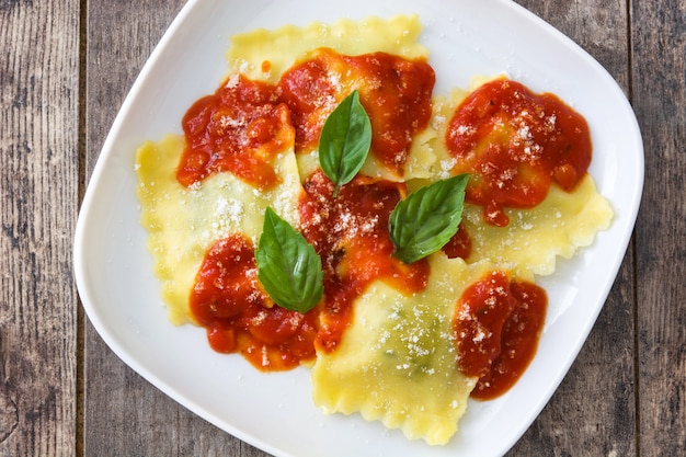 Ravioli with tomato sauce and basil on wooden