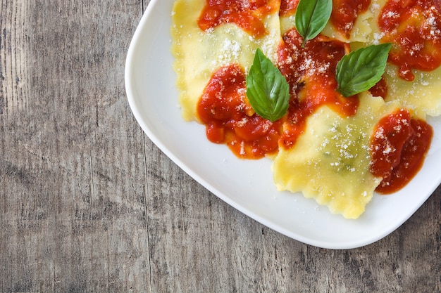 Ravioli with tomato sauce and basil on wooden