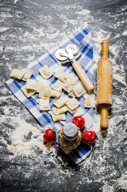 Ravioli with tomatoes and a rolling pin on the fabric.