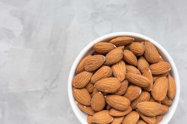 Raw almonds in a porcelain bowl on gray 