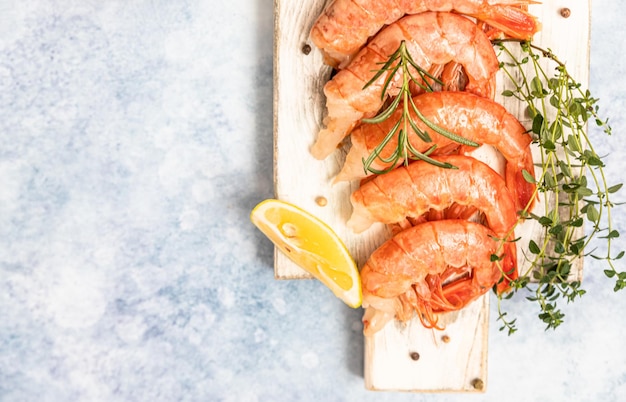 Raw Argentine shrimps on white wooden cutting board with lime herbs and pepper Seafood