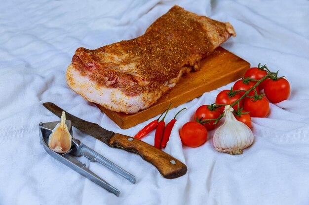 Fette di pancetta cruda con giallo con spezie secche sul bordo bianco