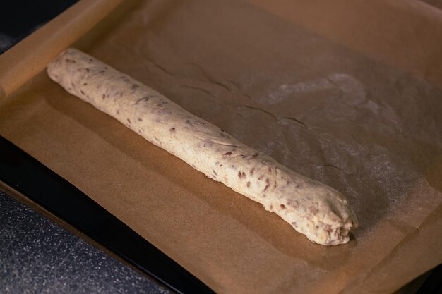 Photo raw baguette dough made from whole grain flour lies on baking paper making bread