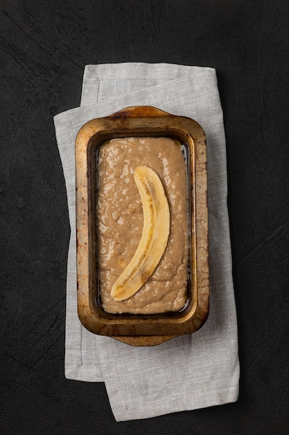 Photo raw banana bread dough in rectangular baking dish on black background