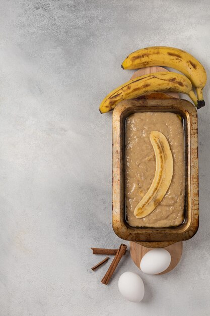 Raw banana bread dough in rectangular shape with ingredients on light background