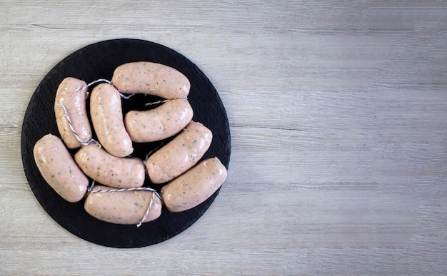 Raw barbecue sausages on a light wooden background close up copyspace