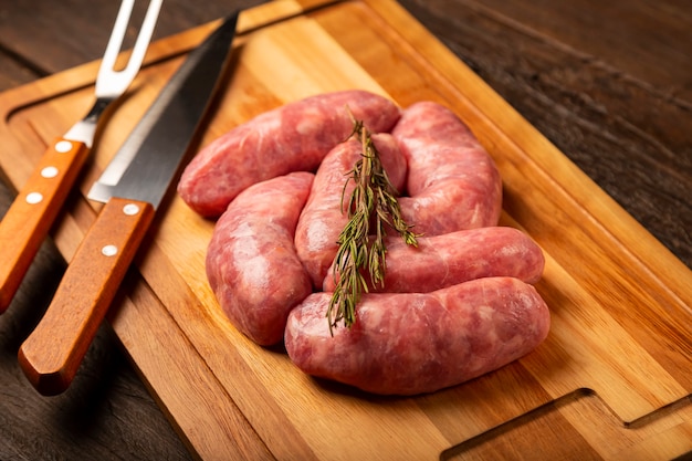 Raw barbecue sausages ready to roast on the wooden table