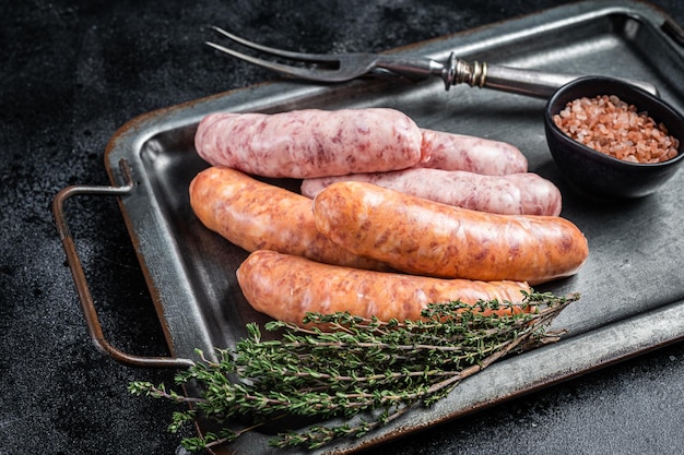 Raw barbecue sausages with spices in kitchen tray Black background Top view