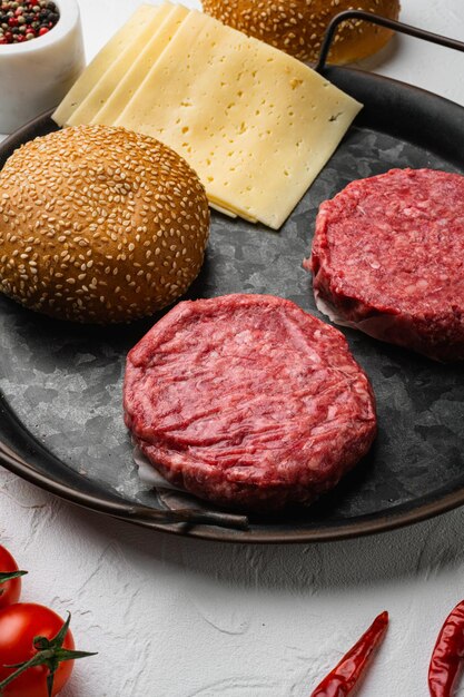 Raw BBQ Beef Burger Cutlets on white stone table background