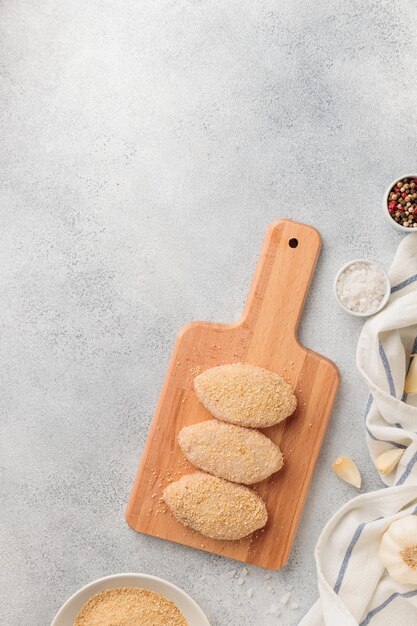 Raw beached meat cutlets on a wooden board