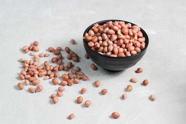 Raw beans in a black bowl Peanut is a leguminous plant belonging to the cultivated family of Fabaceae