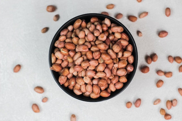 Raw beans in a black bowl Peanut is a leguminous plant belonging to the cultivated family of Fabaceae