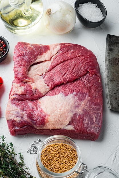 Raw beef belly, beef brisket meat set,with ingredients for\
smoking making barbecue, pastrami, cure, on white stone\
background