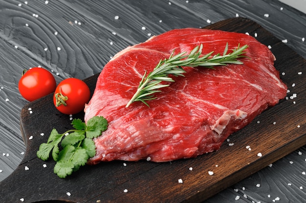 Raw beef fillet piece on wooden board close up