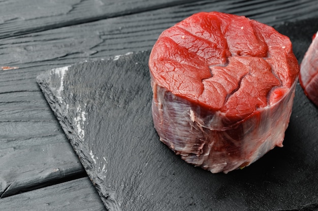 Raw beef fillet steaks on black wooden table