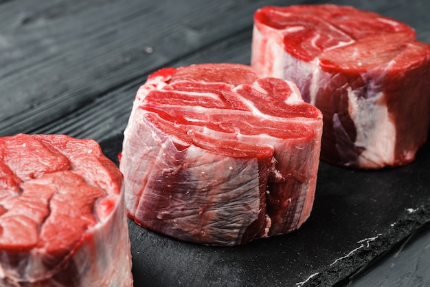 Raw beef fillet steaks on black wooden table