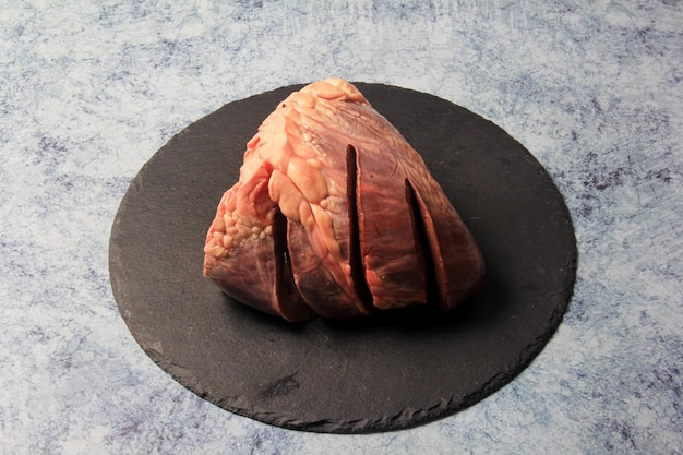 Сырое говяжье сердце на каменной тарелке со специями