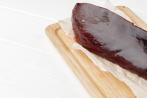 Raw beef liver on wooden board on table