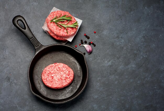 Raw Beef Meat Burger schnitzels en kruiden in een gietijzeren koekenpan bovenaanzicht