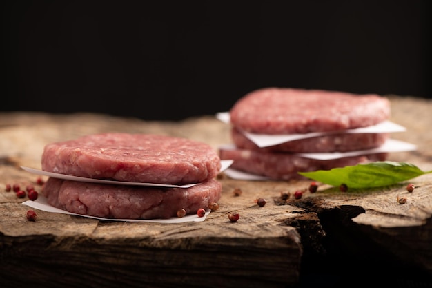 Cotolette di bistecca di hamburger di carne di manzo cruda e fondo di legno di pepe rosso secco