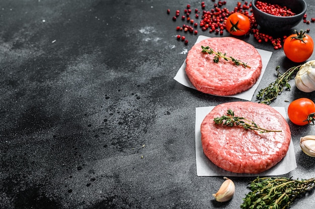 Raw beef meat burgers on a dark background