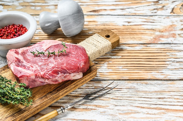 Raw beef meat Club or striploin on the bone steak. White wooden background. Top view.