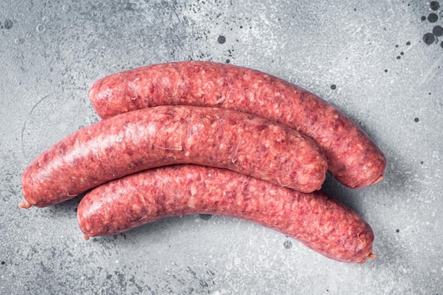 Raw beef meat sausages ready for cooking Gray background Top view