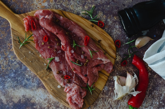 Raw beef meat with spices on a wooden board