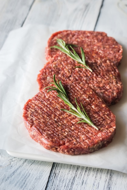 Raw beef patties on the white parchment