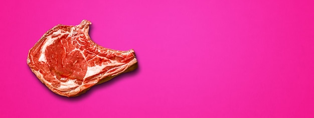 Raw beef prime rib isolated on pink background. top view. horizontal banner