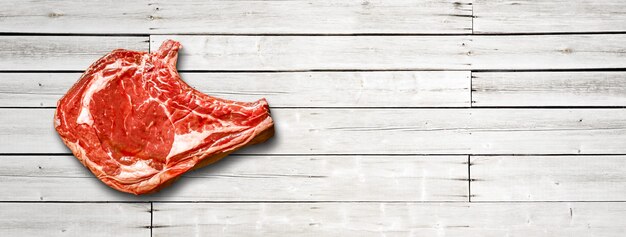 Raw beef prime rib isolated on white wooden background. Top view. Horizontal banner