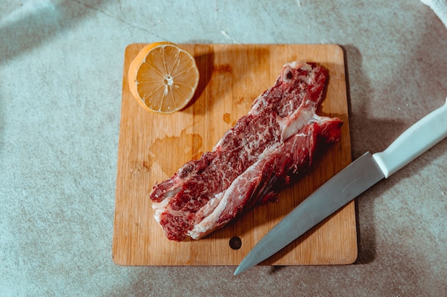 Raw beef ribs on a wooden plate with lemon