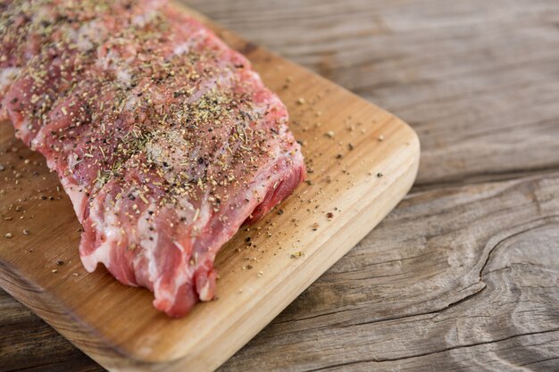 Raw beef ribs on wooden tray against wooden surface