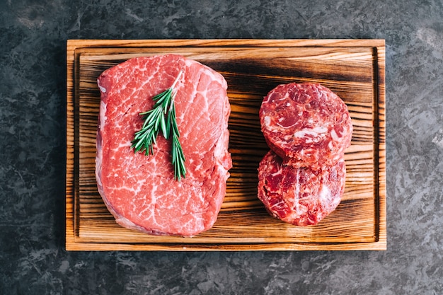 Raw beef steak and minced round steak for burgers on wooden board