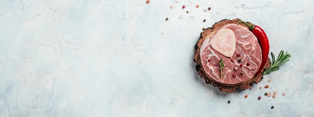 Foto bistecca di manzo crudo osso bucco con erbe e spezie. carne di marmo. ingredienti da cucina. concetto di cibo sano naturale. formato banner lungo. vista dall'alto.