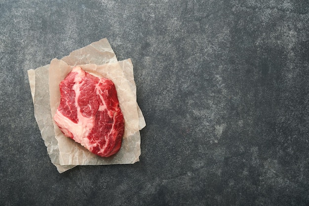 Raw beef steak Raw fresh Chuck roll steak with rosemary salt and pepper on cutting board on dark concrete background Raw beef steak and spices for cooking