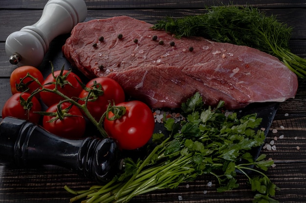 Photo raw beef steak with spices on a dark slate stoneselective focus