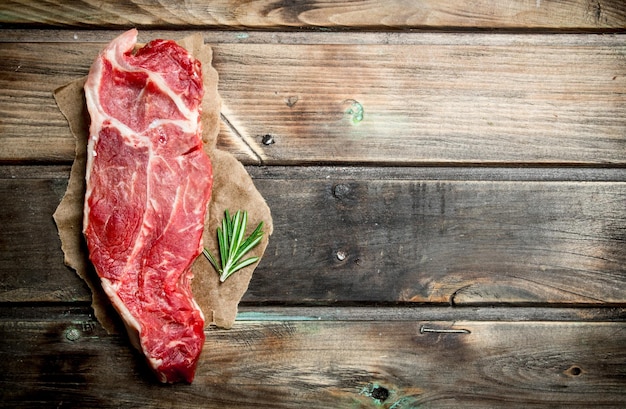 Raw beef steak with a sprig of rosemary