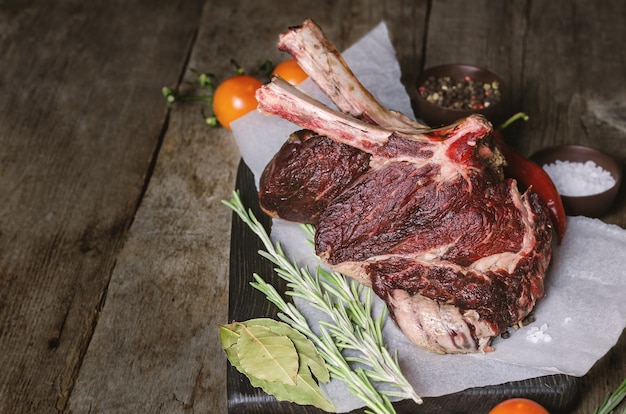 Raw beef steaks with bone on wooden board.