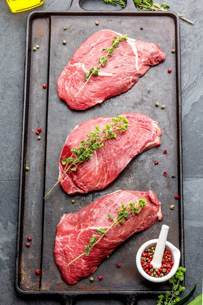 Raw beef steaks with herbs and spices