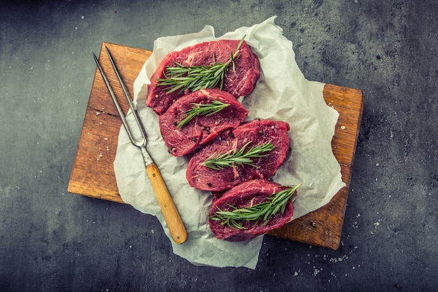 Raw beef steaks with salt pepper and rosemary.
