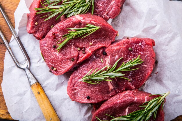 Raw beef steaks with salt pepper and rosemary.