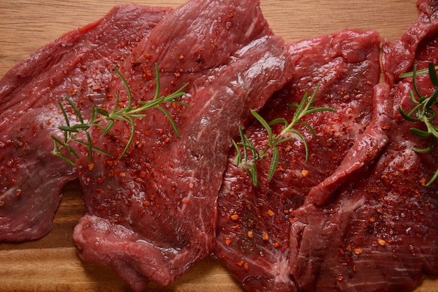 Raw beef steaks with spices and rosemary.